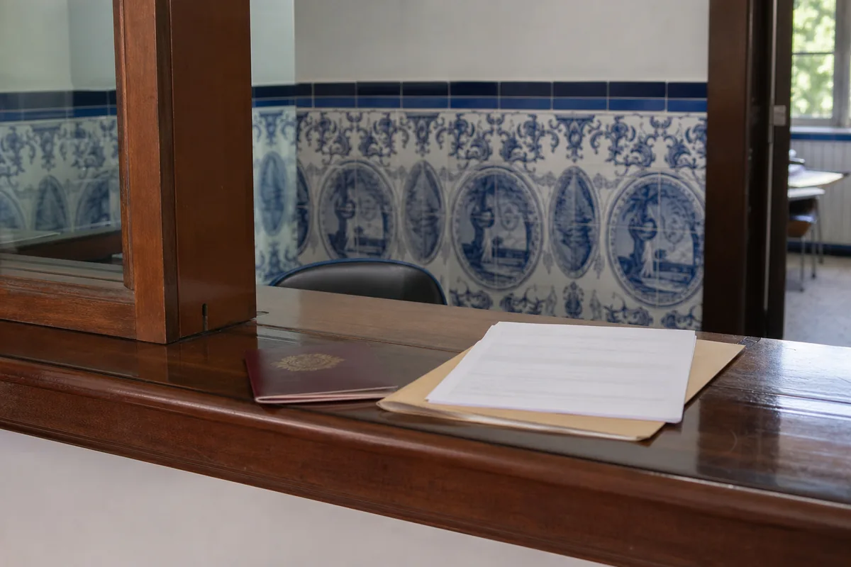 Balcão de atendimento de uma câmara municipal com azulejos e uma pasta de documentos