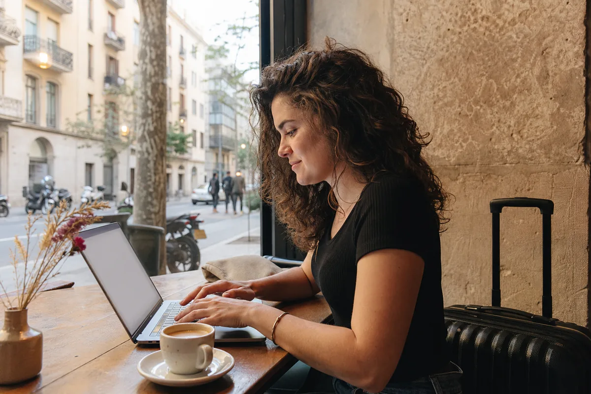 Pessoa preenchendo um pedido online com mala ao fundo